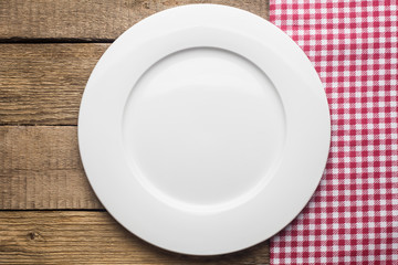 empty plate on a wooden background, a napkin in a red and white cage