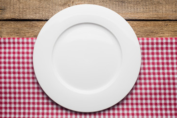 empty plate on a wooden background, a napkin in a red and white cage