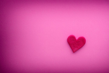 Red heart with small cracks on a pink background