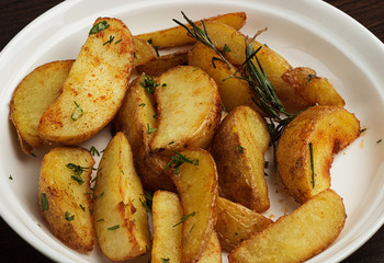 Close up Gourmet Spicy Fried Potato Wedges on Plate with Herb on Top. Isolated on White Background.