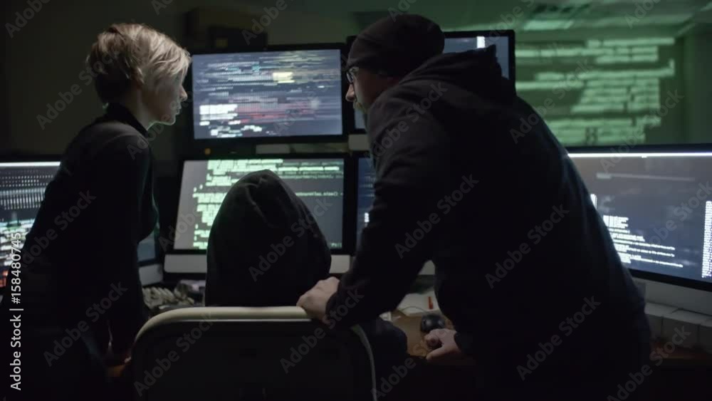 Wall mural rear view of three hackers trying to gain access to web server. man typing commands on six computer 