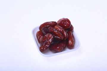 Delicious dried organic dates on bowl isolated over white background.