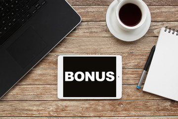 Tablet on desktop with bonus text.