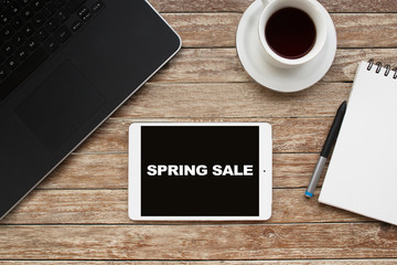 Tablet on desktop with spring sale text.