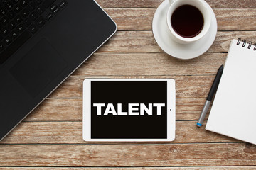 Tablet on desktop with talent text.