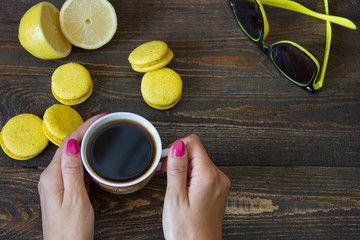 Obraz na płótnie Canvas a girl is drinking coffee with yellow macaroons