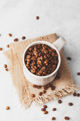 Conceptual Breakfast, Cup with coffee beans on a white concrete background.