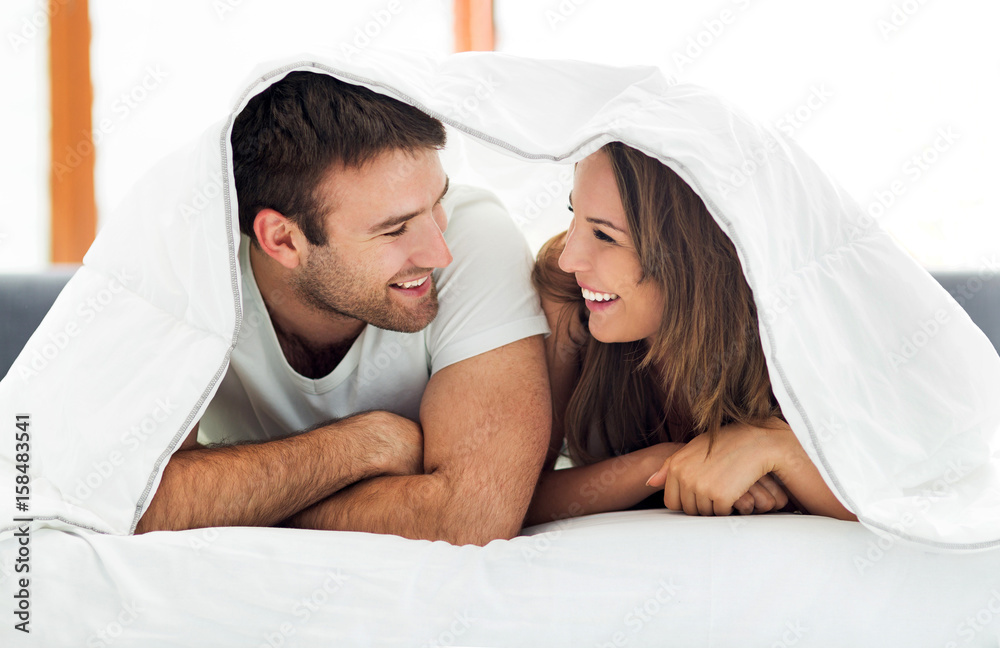 Wall mural Couple under bed covers
