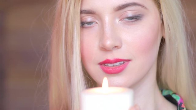 Attractive young women with candle in arms. Never again. Feels sedness and looks in camera
