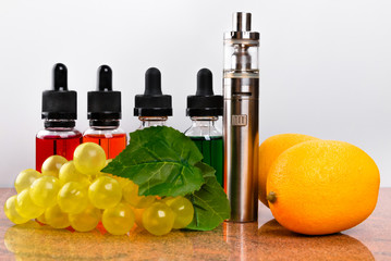 Electronic cigarette, lemons and bunch of grapes on granite surface and white background
