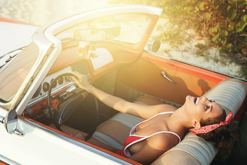 Beautiful and happy woman inside a retro car
