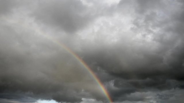 Time Lapse, Rising rainbow cuts colorful arc through clouds after monsoon rainstorm.