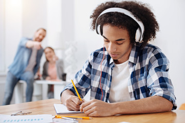 Dedicated young man listening to music while studying