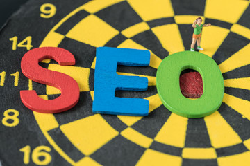 Search engine optimization concept as colorful alphabet abbreviation SEO on dartboard and miniature figure