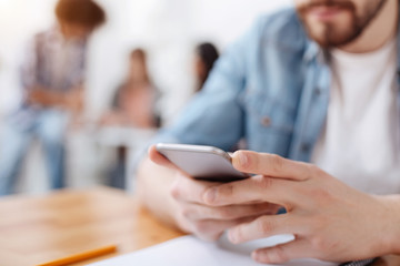 Neat young guy using his smartphone