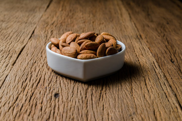 almond in porcelain heart bowl on wooden board