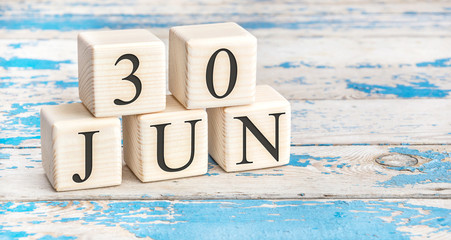 June 30th. Wooden cubes with date of 30 June on old blue wooden background.