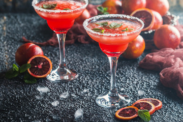 Blood Orange Margarita cocktail with mint and red orange in salt rimmed cocktail glass with tequila, syrup and crushed ice