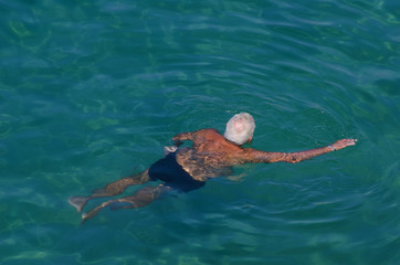 persona mayor con el pelo blanco bañándose en el mar