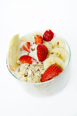Healthy breakfast - yogurt, oat flakes, strawberries, bananas, apples, flax seeds. White background. Vertical photo