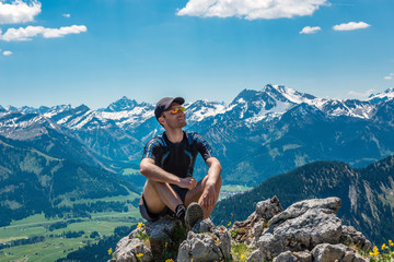 Naklejka premium Happy man sitting on a rock in mountains