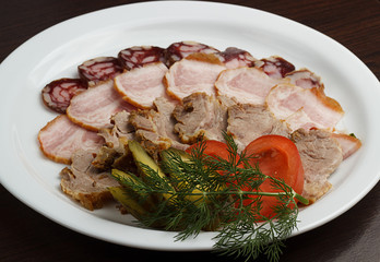 Arranging dried meat with bacon and sausages in wooden basket isolated on white background