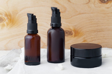 Mockup with cream jar and two brown cosmetic dispensers on linen and wooden background. Pure and minimalistic concept