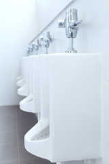 row of white urinals ceramic in public toilet or restroom. selective focus.