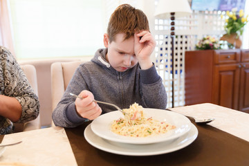 Preteen handsome boy with a plate of pasta refuse to eat