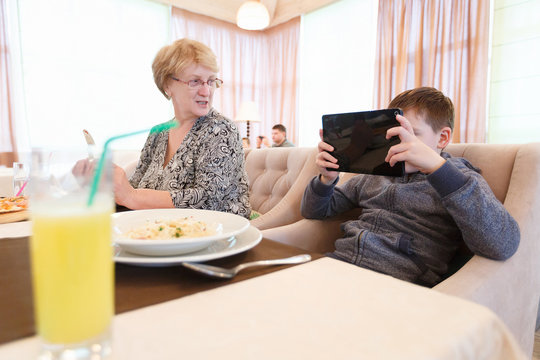 Smiled grandmother taking the common selfie with a child, using a tablet