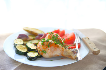 Plate of roast chicken legs, zucchini, fingerling potatoes and tomatoes with copy space