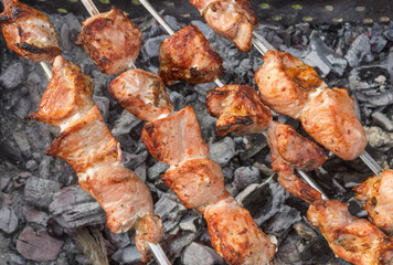 Pork meat cooking outdoor on skewers over smoldering carbon