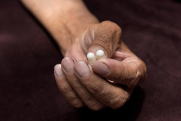 Two white pills in old men's hands . Painful old age. Health care of older people.