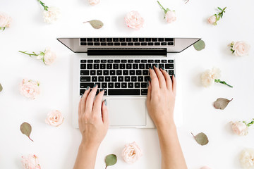 Girl working on laptop and flowers pattern made of beige rose buds on white background. Flat lay, top view. Floral background.