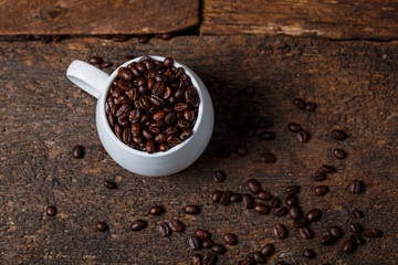 Coffee beans in the cup on wooden background