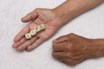 The elderly man is holding the dice with the inscription life. The concept of retirement.