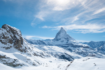 Fototapeta na wymiar Scenic view on snowy Matterhorn peak in sunny day with blue sky and some clouds in background, Switzerland.
