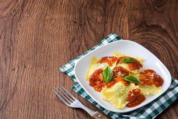 Ravioli with tomato sauce and basil on wooden background. 
