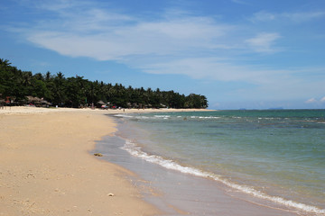 Travel to Island Koh Lanta, Thailand. The view on the sand beach with blue sea and palms on a background on a sunny day.