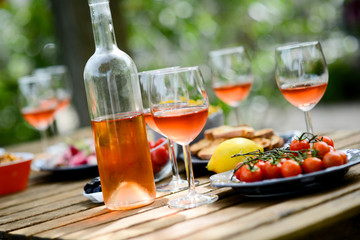 holiday summer brunch party table outdoor in a house backyard with appetizer, glass of rosé wine,...