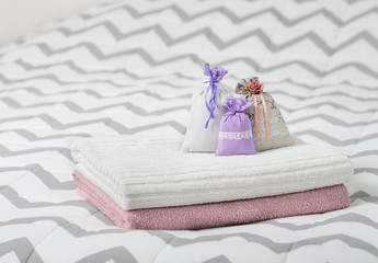 Aromatic potpourri set on bed. Three lavender scent pouches on towels. Scented sachets in bedroom. Fragrance bags for fresh home. Decoration, furnishing and storage items.