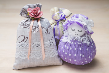 Scented sachets and pouch figure of a girl. Close up of bags filled with lavender on wooden table or board. Decoration, furnishing and storage accessories. Aromatic potpourri set on wood.