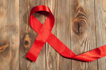 Red ribbon awareness isolated (clipping path)on old aged wood background: World aids day: Symbolic color logo concept raising help campaign on people health public support on HIV, STD heart disease
