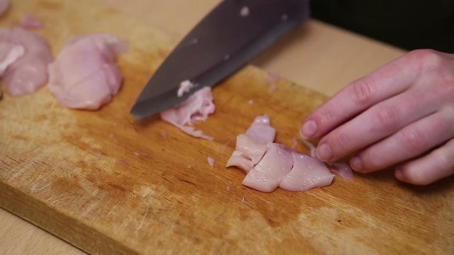 Sliced raw chicken on wooden cutting board 