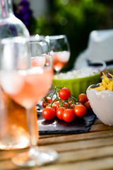 holiday summer brunch party table outdoor in a house backyard with appetizer, glass of rosé wine, fresh drink and organic vegetables
