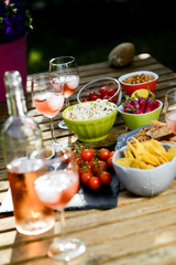 holiday summer brunch party table outdoor in a house backyard with appetizer, glass of rosé wine, fresh drink and organic vegetables