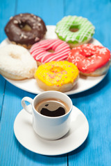 Cup with coffee and donuts on a blue wooden table