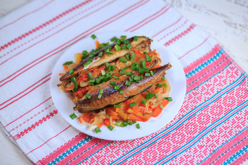 The stuffed mackerel with vegetables and greens on a plate