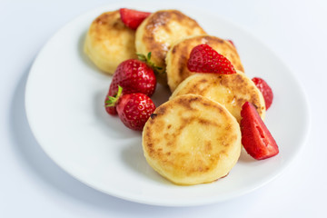 Delicious curd fritters with strawberry on a white plate