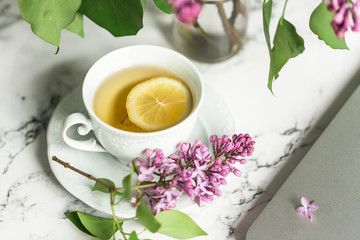 cup of tea and lilacs next to the computer